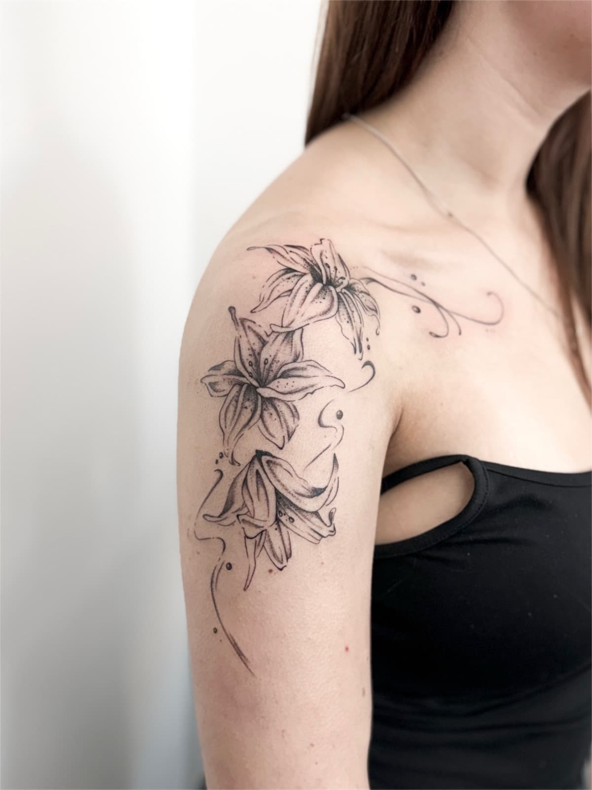 Fine line lilies with dotwork flourishes, shoulder and upper arm