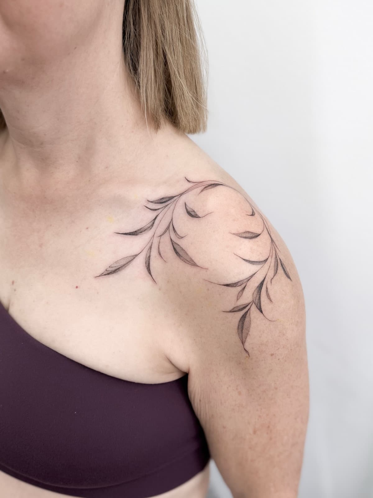 Delicate fine line leafy vine wrapping the shoulder and collarbone