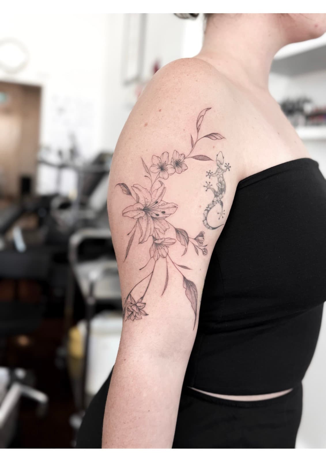 Fine line lily and blossom bouquet with a gecko, upper arm
