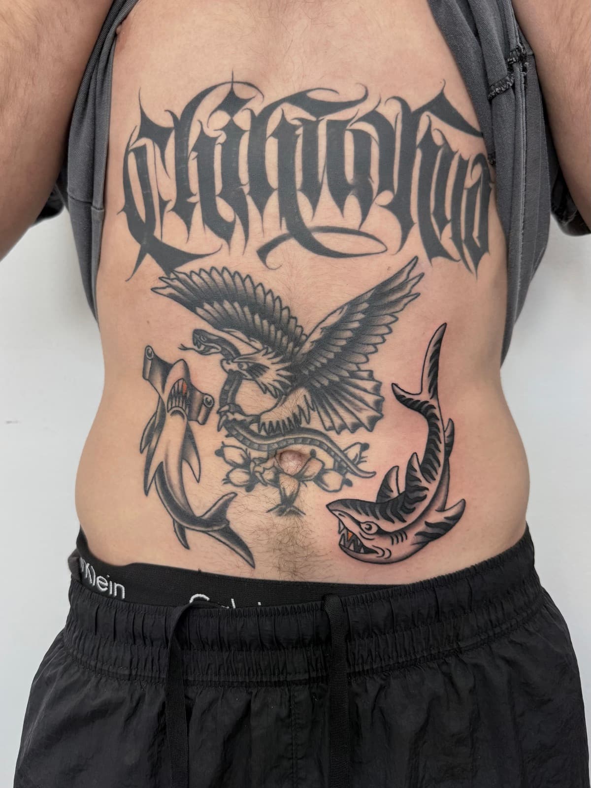 Traditional eagle, sharks and blackletter script stomach piece