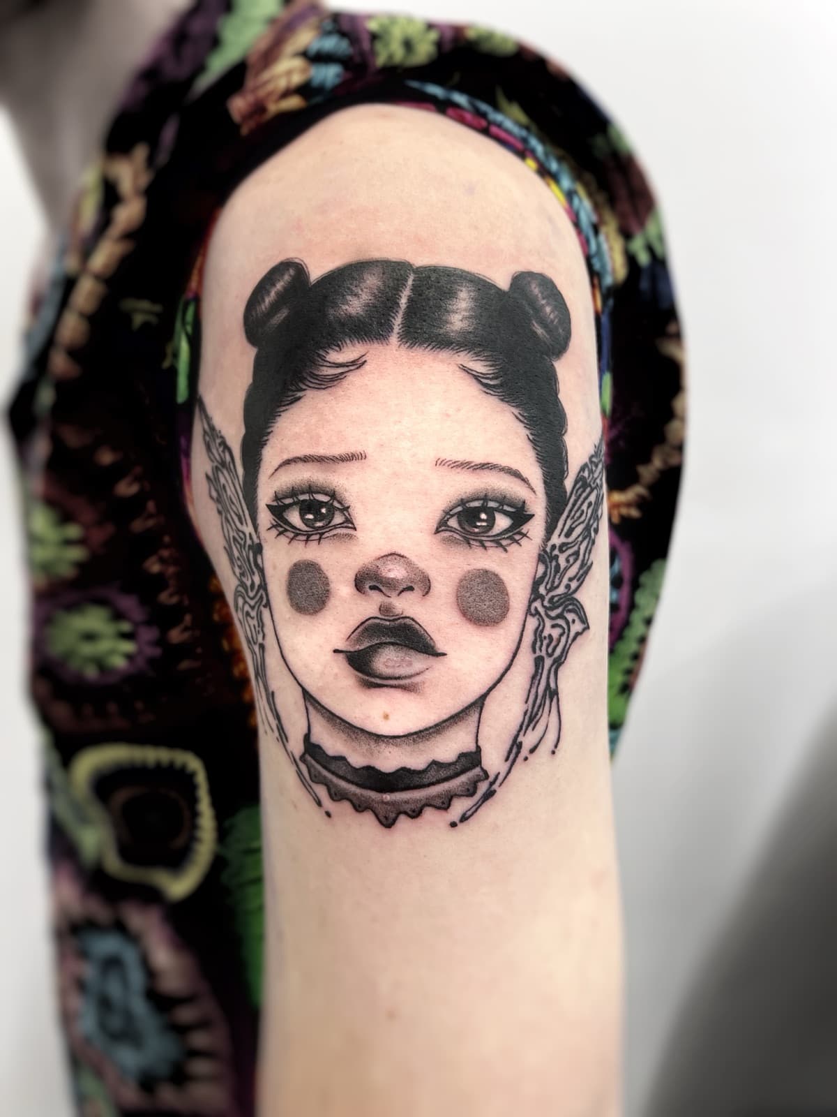 Illustrative doll portrait with moth wings, upper arm