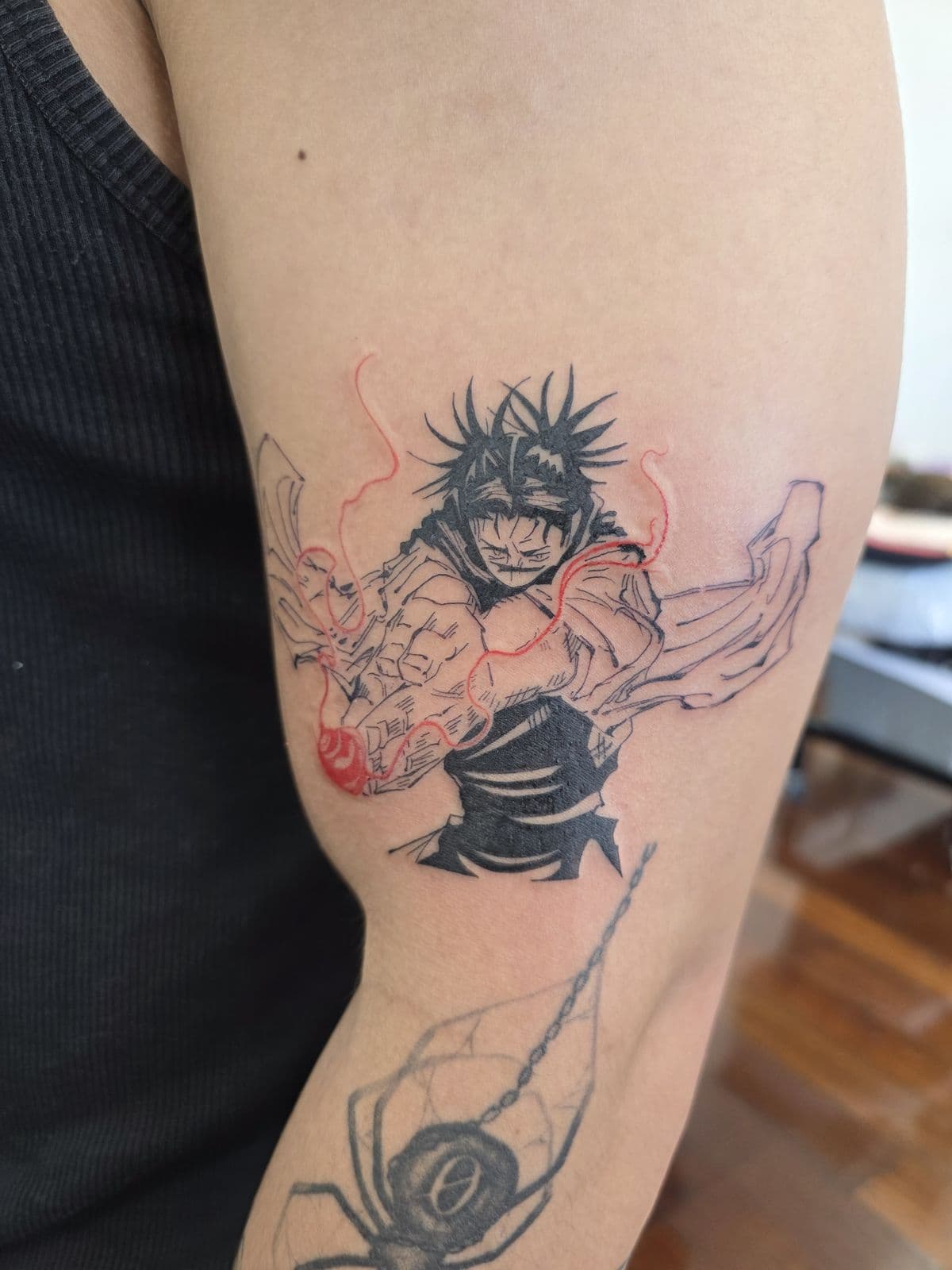 Anime character with red highlights and a hanging spider, upper arm