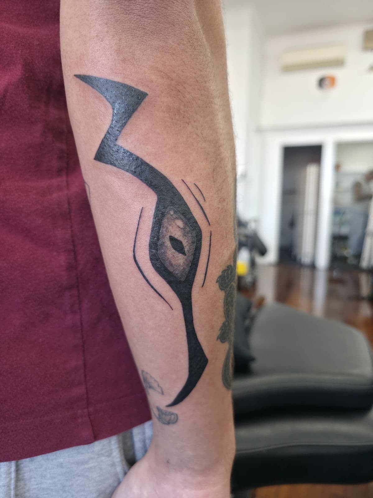 Bold blackwork eye and curved blade, forearm