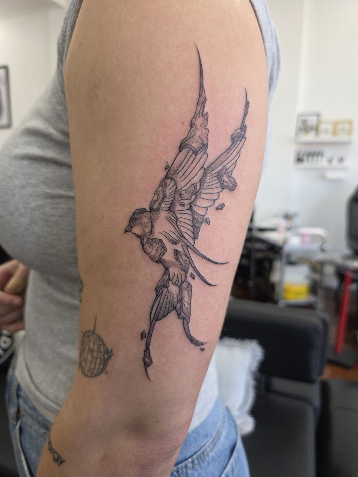 Swallow with flowing feathers in fine line, upper arm